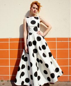 This-is-a-photograph-of-a-woman-standing-against-a-wall-with-a-distinctive-orange-and-beige-tile-pattern-The-woman-is-wearing-a-sleeveless-floor-length-dress-with-a-fitted-bodice-and-a-full