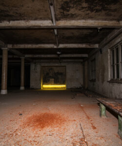 A-dimly-lit-abandoned-room-with-a-bench-peeling-paint-and-a-glowing-yellow-lit-wall