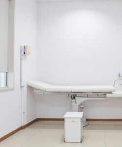 A-minimalist-modern-white-walled-examination-room-with-a-medical-examination-table-a-white-cabinet-and-a-waste-bin