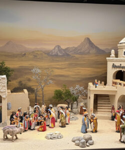 A-photograph-of-a-detailed-colorful-Nativity-scene-with-diverse-figures-a-desert-backdrop-and-intricate-architectural-elements