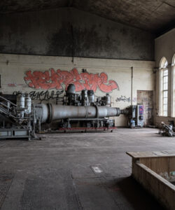 Abandoned-industrial-warehouse-with-graffiti-large-windows-rusting-machinery-and-a-solitary-motorcycle-gritty-atmospheric-setting