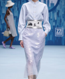 Asian model walking down a runway wearing a blue and white striped shirt and a lavender skirt high quality