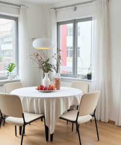 Bright-modern-kitchen-dining-area-with-white-furniture-large-windows-potted-plants-and-a-round-table-set-for-breakfast