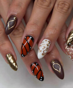 Close up photograph of hands with intricate geometric and abstract nail art in gold black white and brown hues