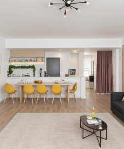 Modern-minimalist-living-room-with-a-grey-couch-yellow-chairs-wooden-floor-white-walls-and-a-TV-in-the-corner