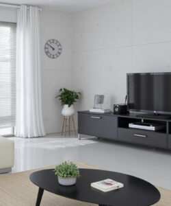 Modern-minimalist-living-room-with-a-large-flat-screen-TV-sleek-black-sideboard-and-white-decor-photographed-in-bright-daylight
