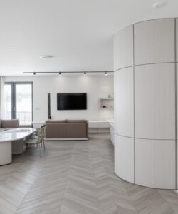 Modern-minimalist-living-room-with-grey-herringbone-flooring-white-walls-large-round-column-flat-screen-TV-and-contemporary-furniture