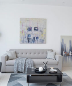 Modern-minimalist-living-room-with-grey-sofa-abstract-art-and-black-chair-contemporary-clean-lines-white-walls-and-geometric-rug