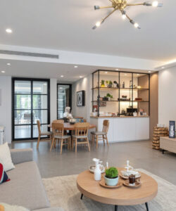 Modern-well-lit-living-room-with-a-grey-sofa-wooden-coffee-table-and-a-TV-adjacent-to-a-kitchen-area