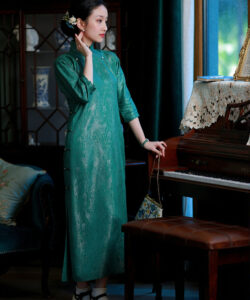 Photo of a woman in a green traditional chinese dress standing next to a piano holding a small purse