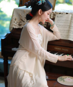 Photograph elegant east asian woman in cream dress playing vintage yamaha grand piano with sheet music and floral decor