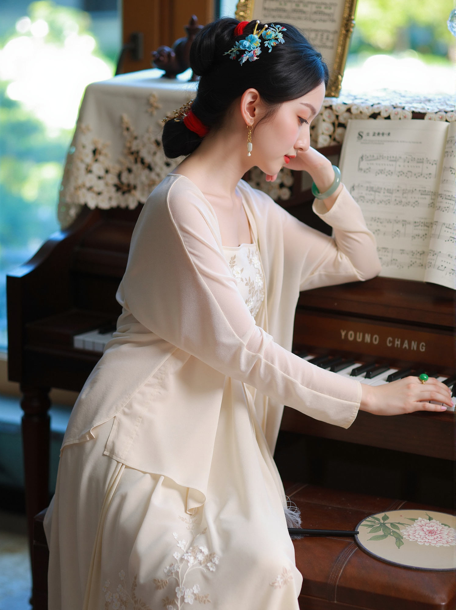 Photograph elegant east asian woman in cream dress playing vintage yamaha grand piano with sheet music and floral decor