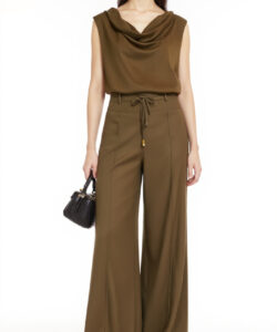 Photograph of asian woman in sleeveless olive green top and wide legged pants holding a black handbag against a plain white background