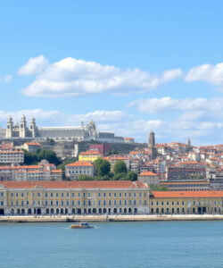 Photograph-of-Lisbon-s-historic-architecture-featuring-the-Belem-Tower-Jeronimos-Monastery-and-red-roofed-buildings-under-a-bright-blue-sky