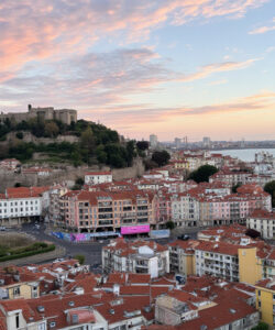 Photograph-of-Porto-Portugal-at-sunset-historic-castle-atop-hill-colorful-rooftops-cityscape-and-river-in-the-background-1