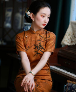 Photograph of a chinese woman in a traditional orange cheongsam playing a piano in an elegant dimly lit room
