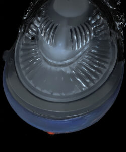 Photograph-of-a-clear-dome-shaped-plastic-container-with-a-silver-ribbed-lid-on-a-black-background