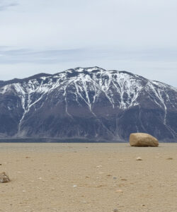 Photograph-of-a-desolate-arid-landscape-with-large-barren-mountains-sparse-rocks-and-a-cloudy-sky-in-the-background