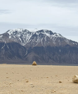 Photograph-of-a-desolate-mountainous-landscape-with-snow-capped-peaks-sparse-rocks-and-a-cloudy-sky-exuding-a-cold-barren-feel