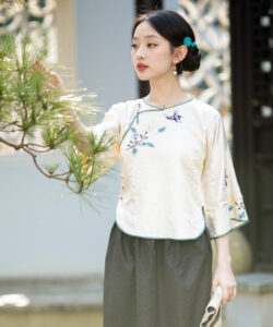 Photograph of a fair skinned asian woman in traditional chinese attire holding a pine branch with a serene elegant expression