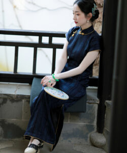Photograph of a fair skinned asian woman in traditional navy blue cheongsam sitting on balcony holding a porcelain plate