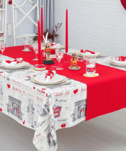 Photograph-of-a-festive-dining-table-with-a-red-tablecloth-white-brick-wall-red-heart-decor-and-heart-shaped-pillows