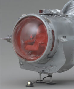Photograph-of-a-futuristic-metallic-spacecraft-cockpit-with-a-red-dome-shaped-window-spiky-protrusions-and-a-small-light-fixture