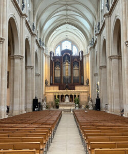 Photograph-of-a-grand-Gothic-cathedral-interior-featuring-tall-arched-columns-wooden-pews-ornate-wooden-organ-and-stained-glass-windows