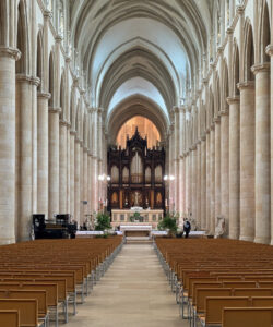 Photograph-of-a-grand-empty-Gothic-cathedral-interior-with-high-arched-ceilings-tall-columns-and-brown-wooden-pews