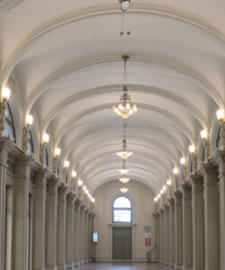 Photograph-of-a-grand-ornate-symmetrical-hallway-with-arched-windows-chandeliers-and-intricate-moldings-exuding-classical-elegance