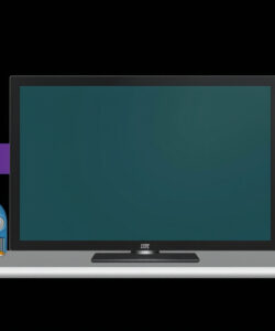Photograph-of-a-modern-office-desk-featuring-a-black-Dell-monitor-two-blue-speakers-two-lamps-and-stacked-books
