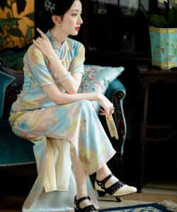 Photograph of a poised asian woman in traditional pastel tie dye cheongsam seated elegantly on a teal velvet sofa