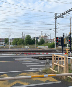 Photograph-of-a-railway-crossing-with-multiple-tracks-signal-lights-and-a-wooden-fence-under-a-cloudy-sky