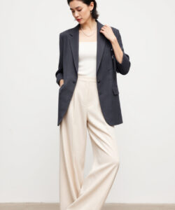 Photograph of a slender asian woman in a gray blazer white top high waisted beige pants and black loafers
