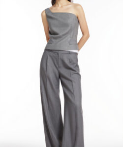 Photograph of a slender asian woman in a grey one shoulder top and high waisted wide leg pants standing against a plain white background