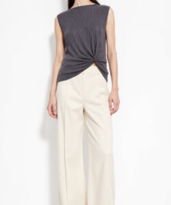 Photograph of a slender asian woman in a sleeveless gray top beige high waisted pants and sandals against a white background