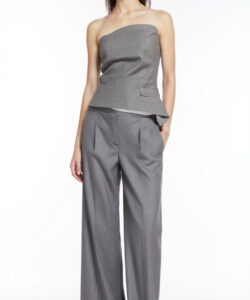 Photograph of a slender asian woman in a strapless grey suit with wide leg pants standing against a plain white background