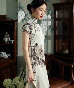 Photograph of a slender asian woman in a traditional white cheongsam dress with floral embroidery set in a vintage room