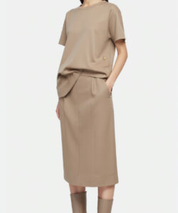 Photograph of a slender asian woman in beige knee length skirt and matching blouse wearing knee high boots against a plain white background