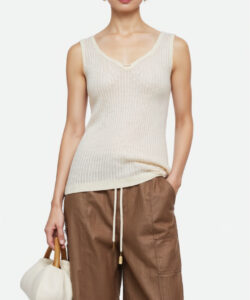 Photograph of a slender asian woman with fair skin wearing a cream tank top brown leather pants and white handbag