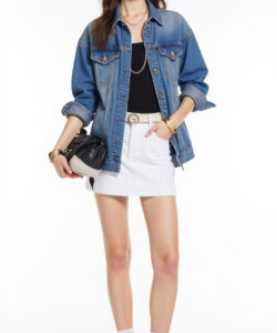 Photograph of a slender fair skinned woman in a denim jacket black top white skirt white socks and sneakers