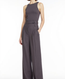 Photograph of a slender fair skinned woman with shoulder length brown hair wearing a sleeveless high waisted gray jumpsuit and white sneakers