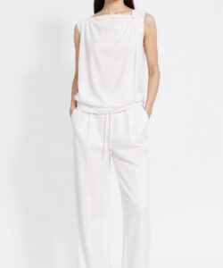 Photograph of a slender light skinned asian woman with long black hair wearing a sleeveless white romper and sandals