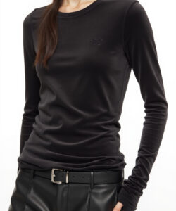 Photograph of a slender light skinned woman in black long sleeve top and leather pants wearing a virtual reality headset