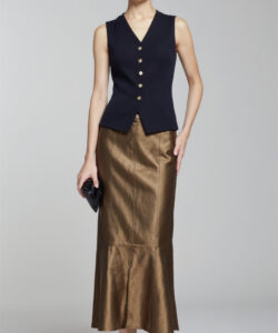 Photograph of a slim asian woman in a sleeveless black top and metallic gold skirt holding a black clutch