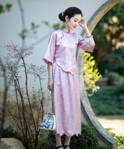 Photograph of a slim asian woman in pale pink traditional chinese attire standing amidst a garden with greenery