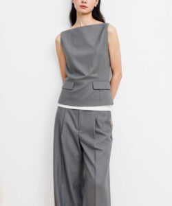 Photograph of a slim asian woman in sleeveless grey tailored suit white blouse and loose pants against a white background