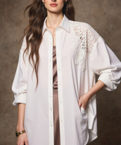 Photograph of a slim fair skinned woman with long brown hair wearing glasses a white lace trimmed shirt and a brown satin dress