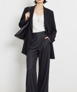 Photograph of a stylish woman in black blazer white tank top high waisted black pants holding a black handbag
