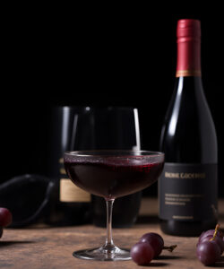 Photograph-of-a-wine-bottle-glass-and-grapes-on-a-wooden-surface-with-a-dark-background-creating-a-rustic-ambiance